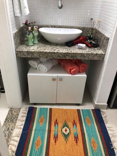 a bathroom with a counter with a sink and a rug at Conforto E Localizacao in Salvador