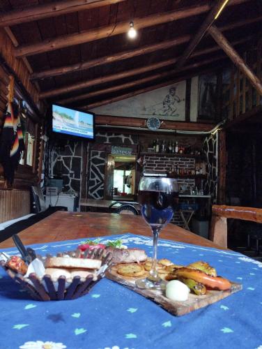 a table with a glass of wine and food on it at Хижа Ловна в Рила in Panichishte