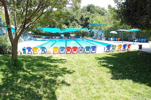 a swimming pool with colorful chairs in front of it at Mazal shell Zimmer in Amirim