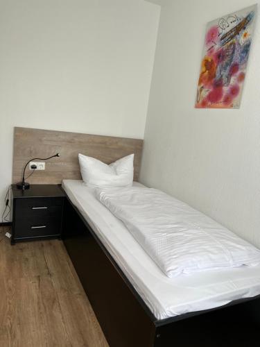a bed with white sheets and a lamp on a table at Hotel My Schildow in Schildow