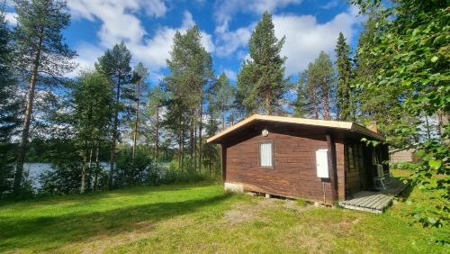 a small cabin in the woods next to a lake at Blockhaus am See in Arvidsjaur