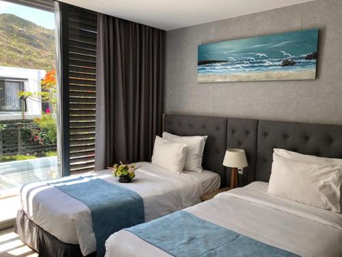 a hotel room with two beds and a window at Oceanami Villas & Beach Club 3 bedroom villa in Long Hai