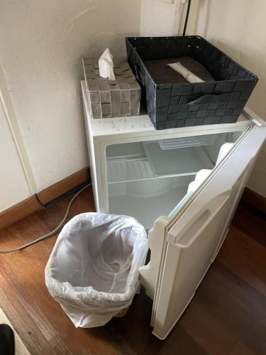 uma pequena prateleira branca com tijolos e uma lata de lixo em ゲストハウス303 em Zamami