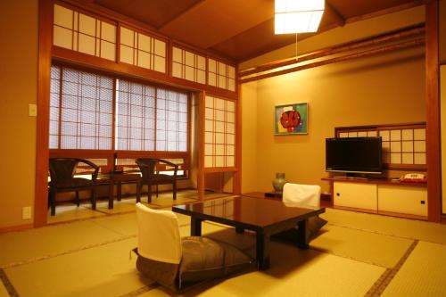 a living room with a table and chairs and a television at 城崎温泉 旅館 つばき乃 - Kinosaki Onsen Ryokan Tsubakino in Toyooka