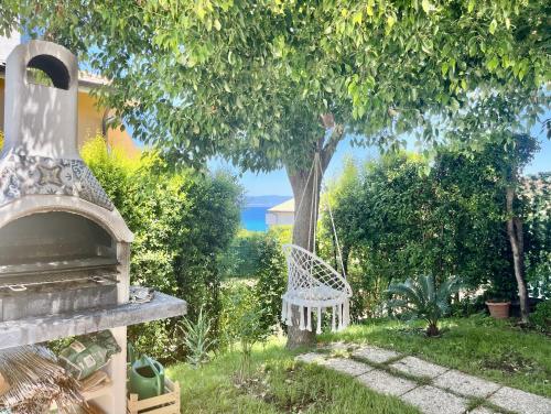 a white chair sitting in the grass under a tree at Villa Solemar in Briatico