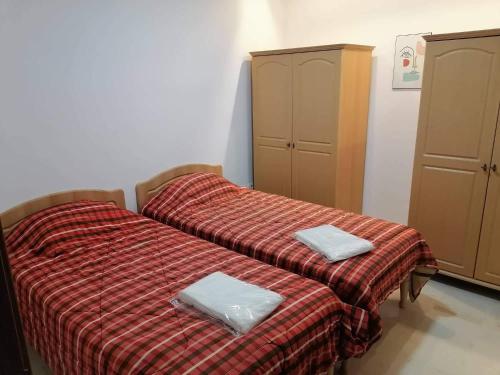 two beds in a room with a red blanket at Zayatine C7 in Sfax