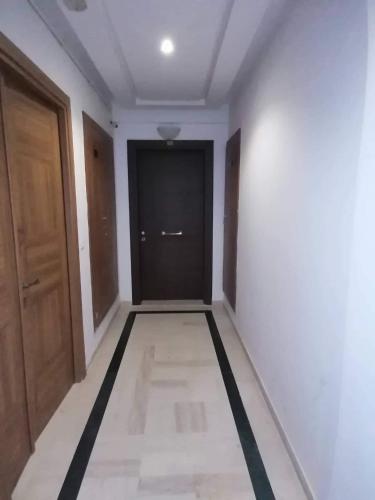 un pasillo con una puerta negra y una pared blanca en Zayatine C7 en Sfax