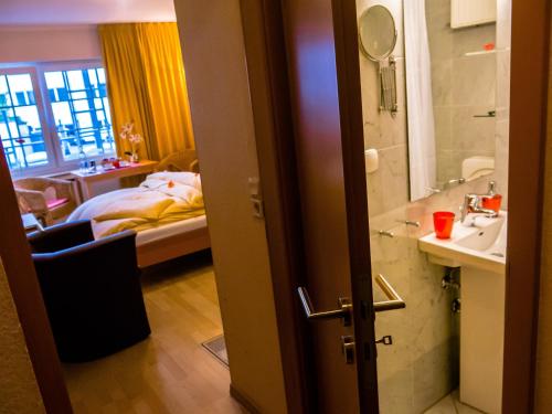 a bathroom with a sink and a bedroom with a bed at The Soho Hotel Altstadt in Düsseldorf