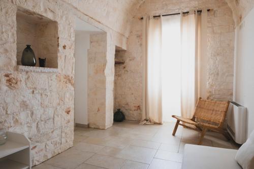 a room with a stone wall with a chair and a window at Dimorae Camà in Cisternino