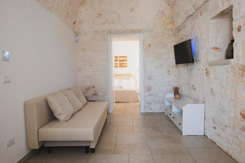 a living room with a couch and a tv on a brick wall at Dimorae Camà in Cisternino