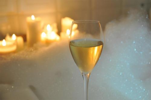 a glass of white wine sitting on a table with candles at Heitlinger Hof in Tiefenbach