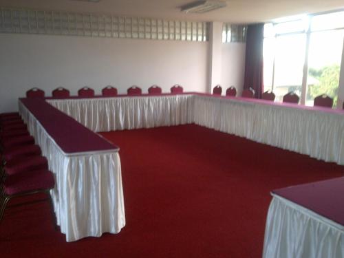 a room with red carpet and white tables and chairs at Pensao Martins in Maputo