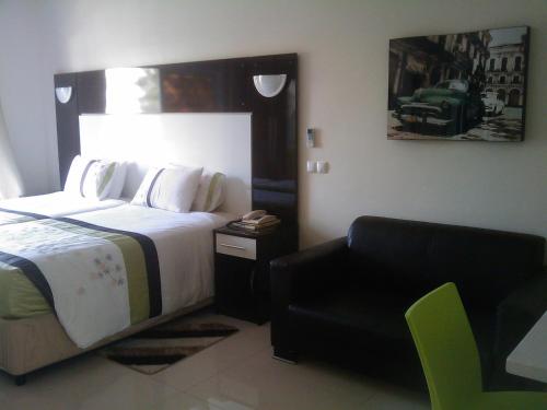 a bedroom with a bed and a chair and a couch at Pensao Martins in Maputo