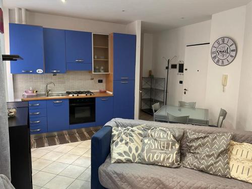 un soggiorno con divano e una cucina con armadi blu di Casa Celeste, bilocale nel pieno centro di Alassio ad Alassio