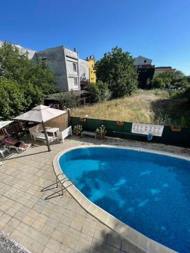 een groot blauw zwembad met een parasol en een patio bij Villa Flora SP apartments in Ravda