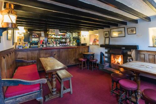 a pub with a bar with a fireplace and stools at The Britannia Inn in Elterwater