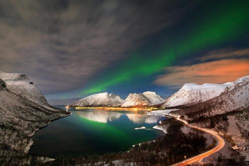 an aurora over a lake and snow covered mountains at Hamn i Senja in Hamn