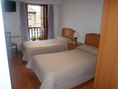 2 Betten in einem Zimmer mit Fenster in der Unterkunft Pension Gades in Cabezón de la Sal