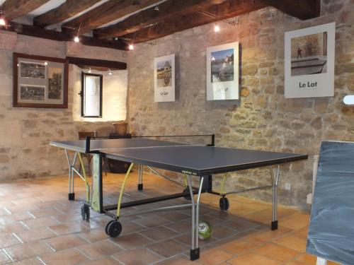 a ping pong table in a room with a brick wall at Gîte Rocamadour L'Oustal de Beline free wifi in Rocamadour