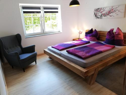a bedroom with a large bed and a chair at Ferienwohnung am Waldrand in Kalletal