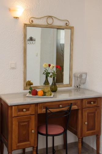 a vanity with a mirror and a chair in a room at Lakki Village in Aegiali