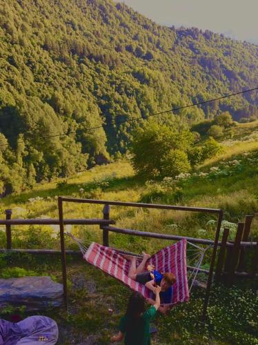 two children sitting in a hammock with a view of a mountain at Qaldea Resort in Ushguli