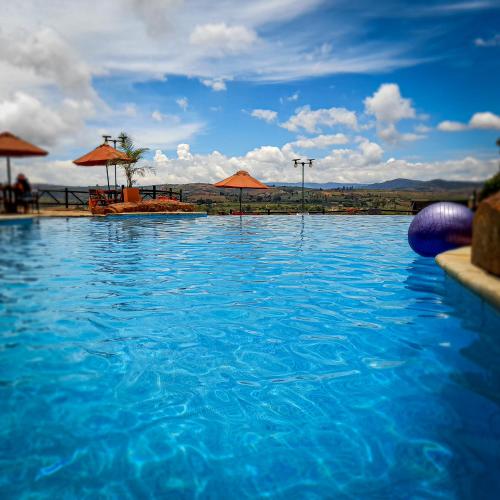 a swimming pool with blue water and umbrellas at Hotel Las Rocas Resort Villanueva in Villanueva