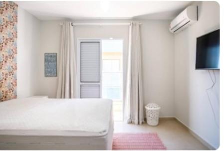 um quarto branco com uma cama e uma janela em Apartamento Top em Itaguá em Ubatuba