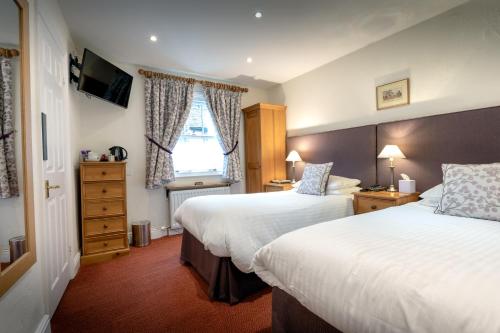 a hotel room with two beds and a window at The Britannia Inn in Elterwater