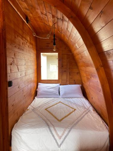 a bed in a wooden cabin with a window at The tiny black bird in Fajã da Ovelha