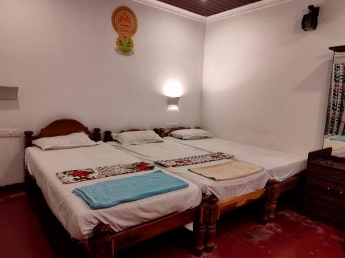 two twin beds in a room with white walls at Marari Das Beach Villa in Mararikulam