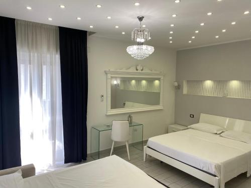 a bedroom with two beds and a mirror and a chandelier at Maison De luxe in Pompei