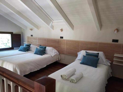 2 camas en una habitación con almohadas azules y blancas en La Campa de FaedoAngelina, en Cudillero