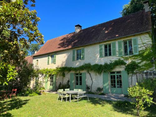 an old house with a picnic table in the yard at Le Clos Chalmon Chambre d'hôte in Montignac