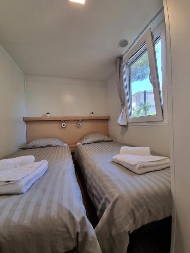 two beds in a small room with a window at Premium Mobile Home ZEN SPOT 277 in Jezera