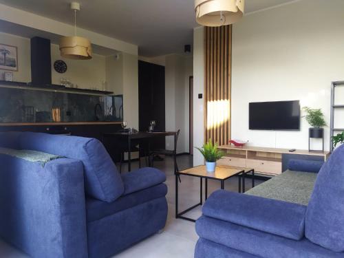 sala de estar con 2 sillas azules y TV en Apartament Burgund Wyspa Sobieszewska, en Gdansk