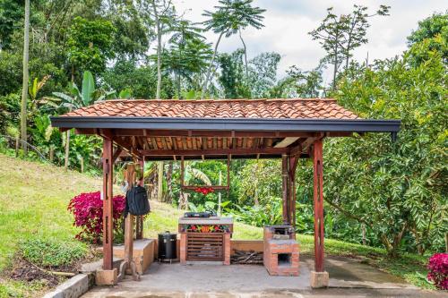 a wooden gazebo in a garden at Agradable cabaña cafetera con jacuzzi a 12 min del centro de pereira in Pereira