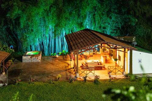 a house in front of a forest with green lights at Agradable cabaña cafetera con jacuzzi a 12 min del centro de pereira in Pereira