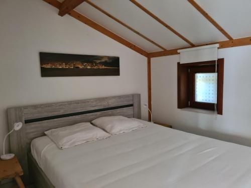 ein weißes Bett in einem Zimmer mit Fenster in der Unterkunft Griad in de Duinen in De Haan