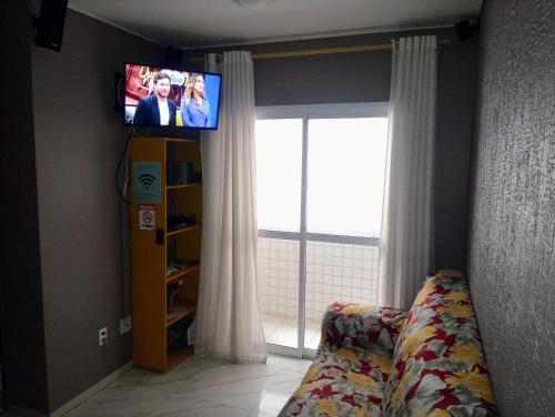 a living room with a tv and a couch and a window at Apartamento Vidal con Wi-Fi Praia Grande Avi in Praia Grande