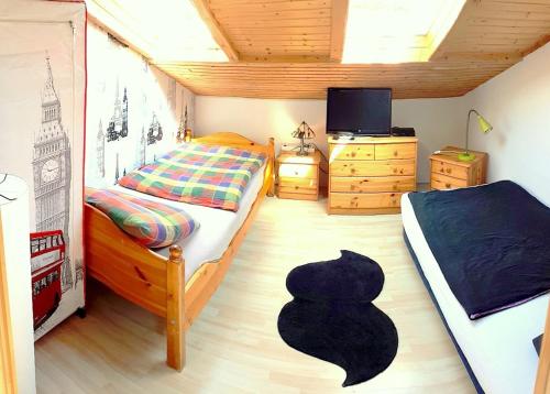 ein Schlafzimmer mit einem Bett, einem TV und einem Stuhl in der Unterkunft Gästehaus Möbius in Markt Erlbach