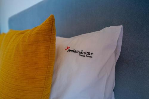 a yellow and white pillow with a red logo on it at FLH Funchal Artistic Apartment with Balcony in Funchal