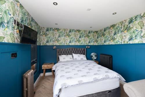 a blue bedroom with a bed and a blue wall at The Caswell bay hide out in Swansea