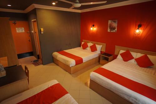 - une chambre d'hôtel avec 2 lits aux murs rouges dans l'établissement V HOTEL, à Teluk Intan
