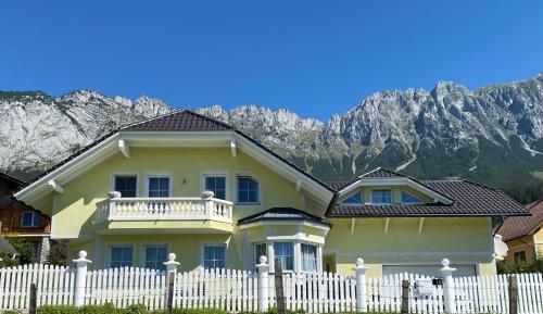 a yellow house with a white fence in front of a mountain at Ferienwohnung Schmid in Sankt Martin am Grimming