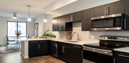 a kitchen with black cabinets and a stove top oven at Lake Eola Apartments by Barsala in Orlando