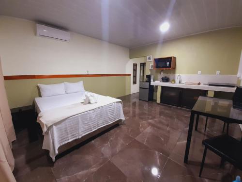 1 dormitorio con 1 cama blanca y cocina en Cabaña Rural Pura Vida, en Fortuna