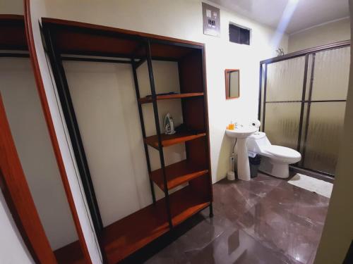 a bathroom with a toilet and a glass door at Cabaña Rural Pura Vida in Fortuna