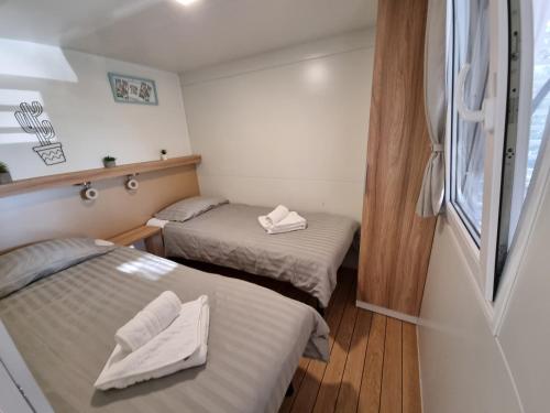2 łóżka w małym pokoju z oknem w obiekcie Premium Mobile Home ZEN SPOT 280 w mieście Jezera