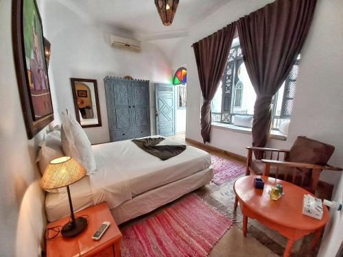 a bedroom with a bed and a chair and a table at Dar Silsila in Marrakesh